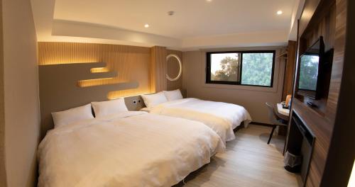 Habitación de hotel con 2 camas y TV en Alishan Shermuh Tourist Hotel, en Zhongzheng