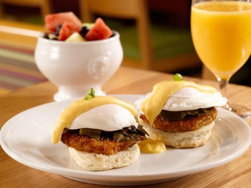 two sandwiches on a plate with a bowl of fruit at Crowne Plaza Charleston by IHG in Charleston