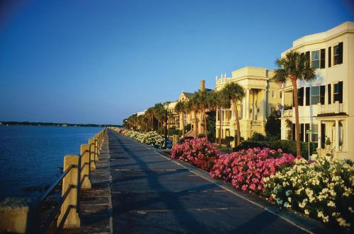 a walkway next to the water with houses and flowers at Crowne Plaza Charleston by IHG in Charleston