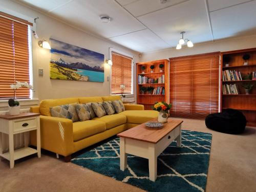 a living room with a yellow couch and a table at Macadamia Retreat - City Central Hygge in Rotorua
