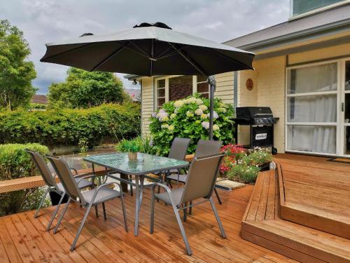 a table and chairs with an umbrella on a deck at Macadamia Retreat - City Central Hygge in Rotorua