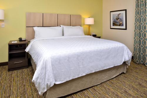 a large bed in a hotel room with a white bedspread at Candlewood Suites - Lodi by IHG in Lodi