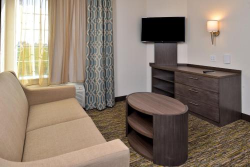 a hotel room with a couch and a tv and a table at Candlewood Suites - Lodi by IHG in Lodi