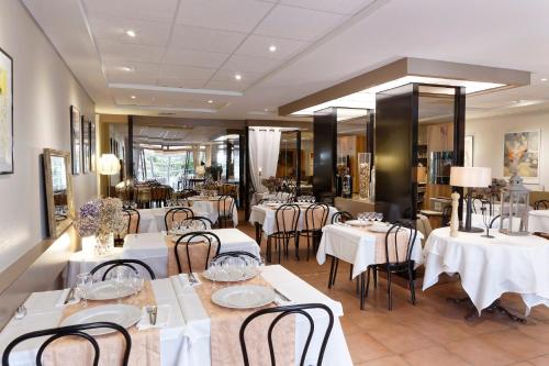 une salle à manger avec des tables et des chaises blanches dans l'établissement Logis Hôtel L'Auzeraie, à Ax-les-Thermes