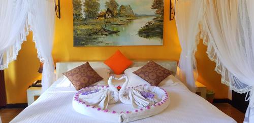 a bedroom with a white bed with a painting at Flower Garden Lake Resort in Tissamaharama