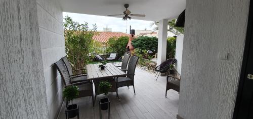 patio z drewnianym stołem z krzesłami i wentylatorem sufitowym w obiekcie Green Garden Gajac Apartman w mieście Skunca
