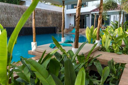 a resort pool with two beds and plants at By The Sea Koh Mak Boutique Guesthouse in Ko Mak
