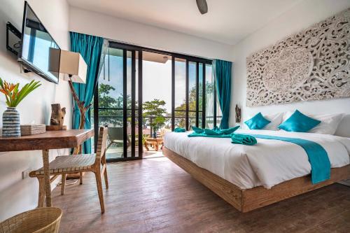 a bedroom with a large bed and a desk with a computer at By The Sea Koh Mak Boutique Guesthouse in Ko Mak
