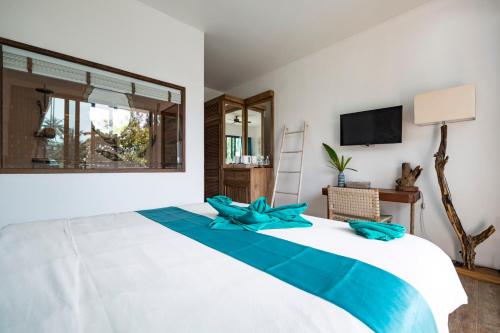 a bedroom with a large bed with blue pillows at By The Sea Koh Mak Boutique Guesthouse in Ko Mak