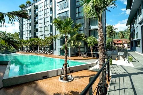 Citygate Kamala Resort and Residence في شاطئ كامالا: مسبح فيه نخل امام مبنى