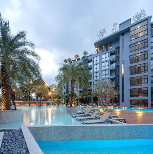 a swimming pool with lounge chairs in front of a building at Citygate Kamala Resort and Residence - Official Account in Kamala Beach