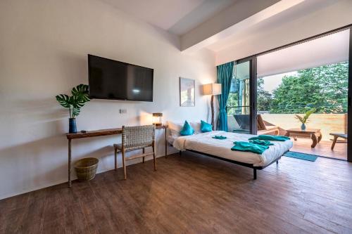 a bedroom with a bed and a tv on a wall at By The Sea Koh Mak Boutique Guesthouse in Ko Mak