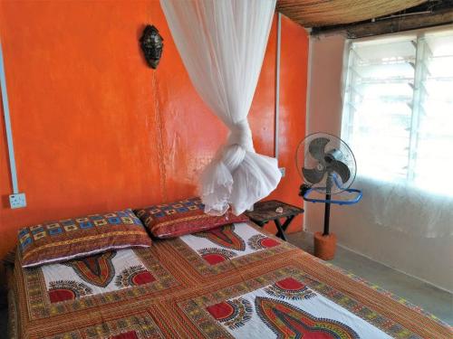 a bedroom with a bed with an orange wall at A&Y Wild Camp Ghana in Keta