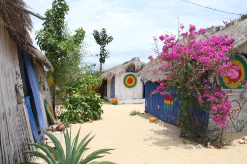 a group of huts with pink flowers in a courtyard at A&Y Wild Camp Ghana in Keta