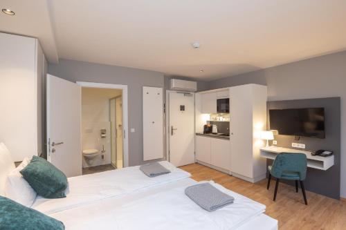 a bedroom with two beds and a desk and a television at Wilmas Apartments by Arbio in Vienna