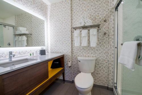 a bathroom with a toilet and a sink and a mirror at Holiday Inn Edmonton South - Evario Events by IHG in Edmonton