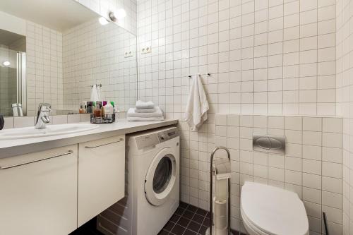 a white bathroom with a washing machine and a sink at Tjuvholmen I, As Home in Oslo