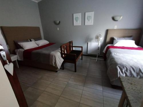 a hotel room with two beds and a chair at Stew s Room in Polokwane