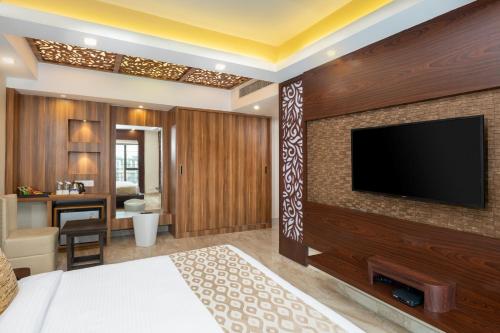 a hotel room with a flat screen tv on a wall at Cygnett Style Tania's in Siliguri