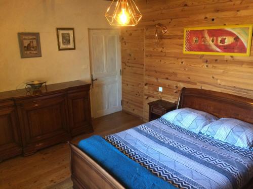 ein Schlafzimmer mit einem Bett und einer Holzwand in der Unterkunft Le Maquis in Charmes