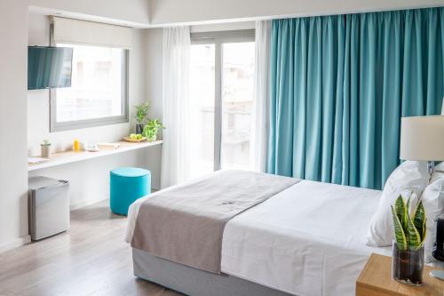 a bedroom with a bed with blue curtains and a window at CHROMA FASHION ROOMS & APARTMENTS in Athens