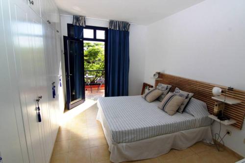 1 dormitorio con 1 cama con cortinas azules y ventana en BAHIA MELONERAS II 62, en Meloneras
