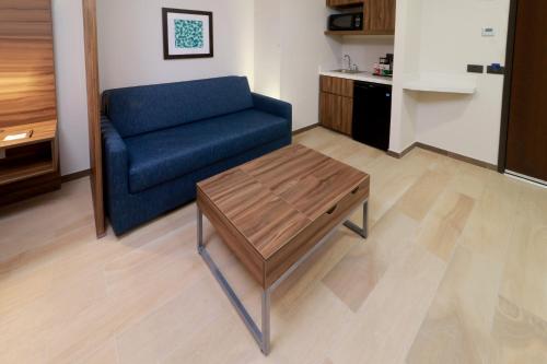 a living room with a blue couch and a coffee table at Holiday Inn Express & Suites - Playa del Carmen by IHG in Playa del Carmen