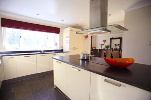una cocina con armarios blancos y un cuenco rojo en una encimera en The Bridge House, Dunbar en Dunbar