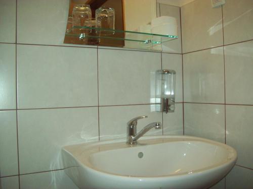 a white bathroom with a sink and a mirror at Rooms Vukša in Donji Lapac