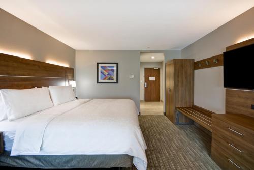 a bedroom with a large bed and a flat screen tv at Holiday Inn Express & Suites - Houston NASA - Boardwalk Area by IHG in Seabrook
