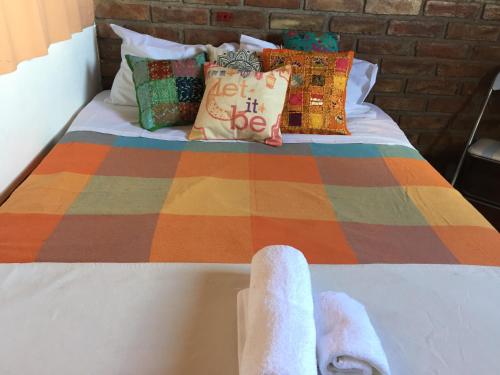 Una cama con una manta colorida y toallas. en Departamento Privado para dos personas en Mendoza en Godoy Cruz