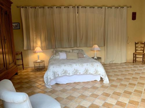 a bedroom with a bed with two lamps and a chair at Gite Chez Un Producteur de Fruits. in Boulbon
