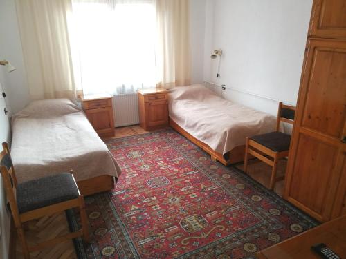 a bedroom with two beds and two chairs and a window at Guest Rooms Metaksinovi in Chepelare