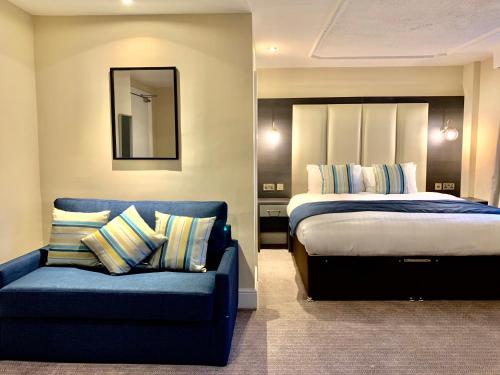 a bedroom with a bed and a blue couch at Trafford Hall Hotel Manchester, Trademark Collection by Wyndham in Manchester