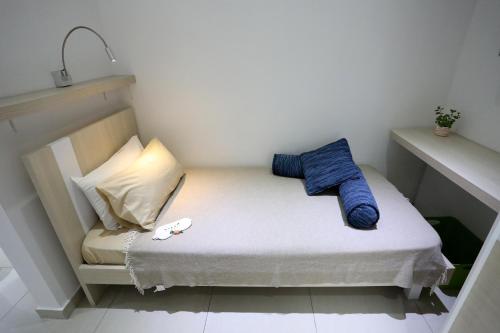 a small bed in a small room with blue pillows at Escape to St Julians in St Julian's