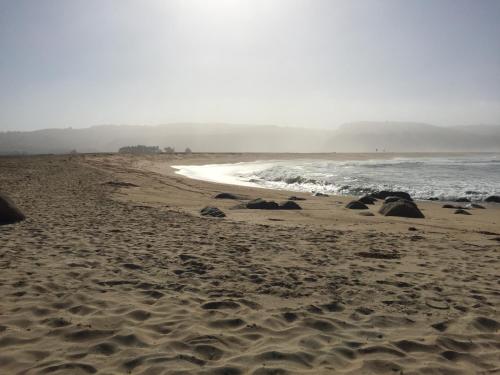 a beach with sand and the ocean on a cloudy day at Tunquen Magico in Tunquen
