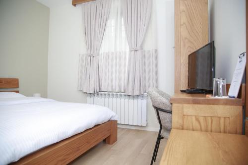 a bedroom with a bed and a desk with a television at JOEN Village in Librazhd