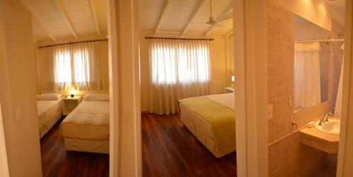 Habitación de hotel con 2 camas y lavamanos en La Posada Hotel en Pinamar