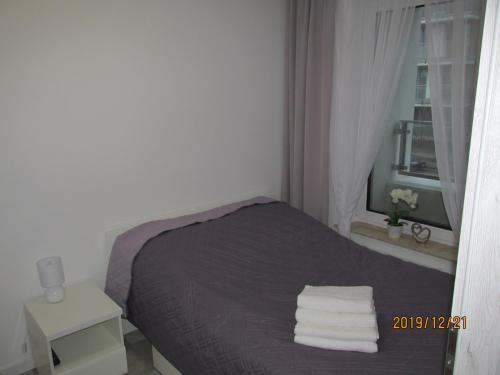 a small bedroom with a bed with towels on it at Apartament Oskar in Kołobrzeg