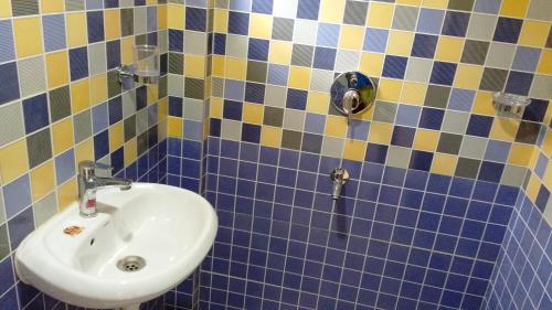 a blue and yellow tiled bathroom with a sink at DSK Studio Apartment, Siolim, Goa. in Siolim