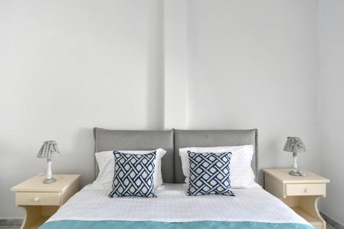 a bed with blue and white pillows and two night stands at White Rooms Paros in Naousa