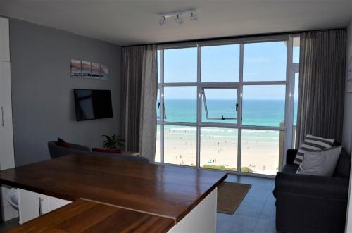 sala de estar con mesa y vistas a la playa en 808 St Tropez, en Ciudad del Cabo