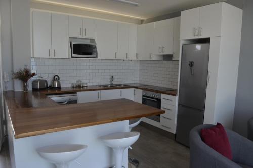 a kitchen with white cabinets and a stainless steel refrigerator at 808 St Tropez in Cape Town