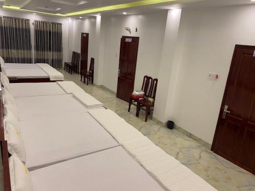 una camera con una fila di letti e sedie di Hoàng Sa Hotel a Xóm Nhà Mát