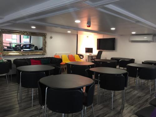 a room with tables and chairs and a tv at Rahman Hostel in Manchester