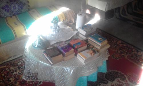 stos książek siedzących na stole z lampą w obiekcie maison isabel w mieście Boumalne Dades