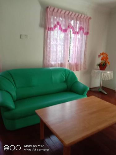 a green couch in a living room with a table at OPRO S&S Homestay Pagoh Malay Only in Muar