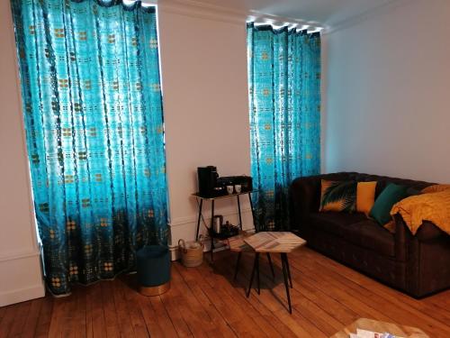 uma sala de estar com cortinas azuis e um sofá em Le 43-4 avec sauna privatif em Le Puy-en-Velay