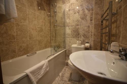 a bathroom with a tub and a toilet and a sink at Westone Manor Hotel in Northampton
