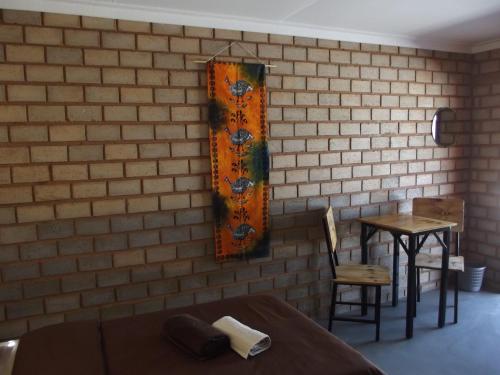 a room with a brick wall with a bed and a table at Stop 'n Stay Otavi Rest Camp in Otavi